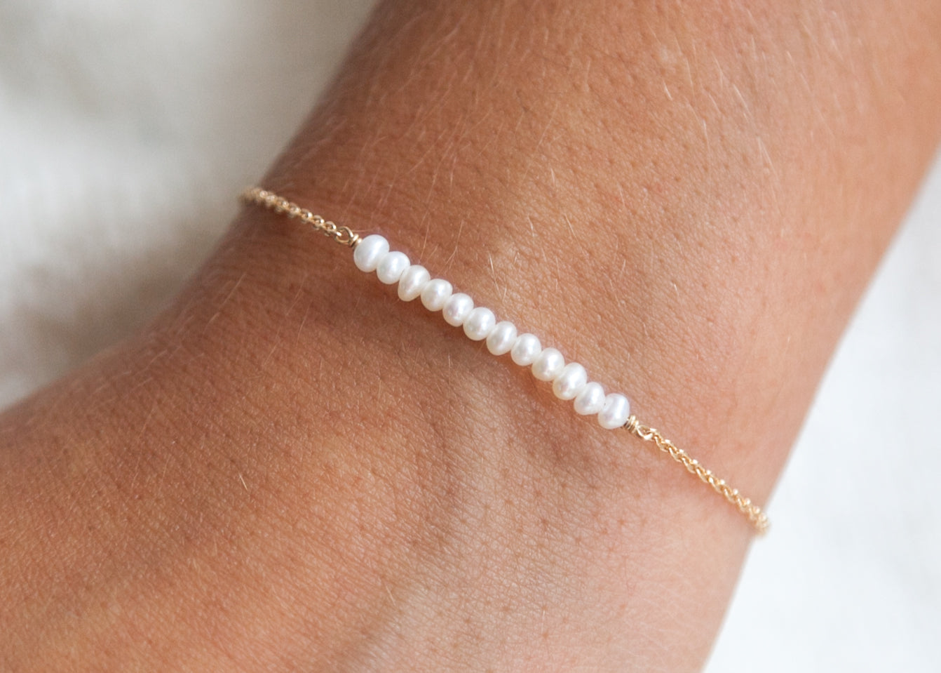 Bracelet fin et perles blanches plaqué or